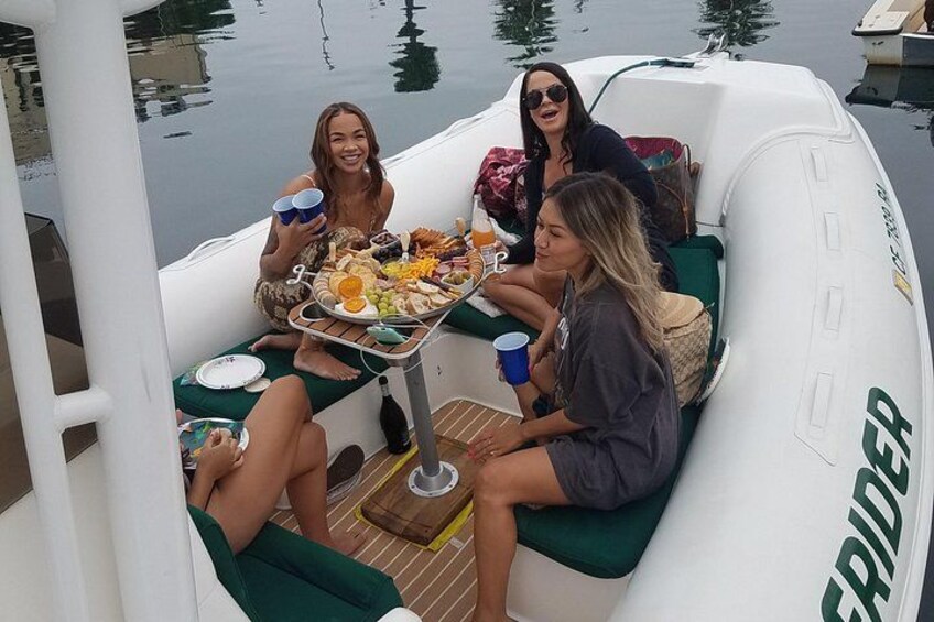 A group of people on a boat with a table full of food and drinks. 2