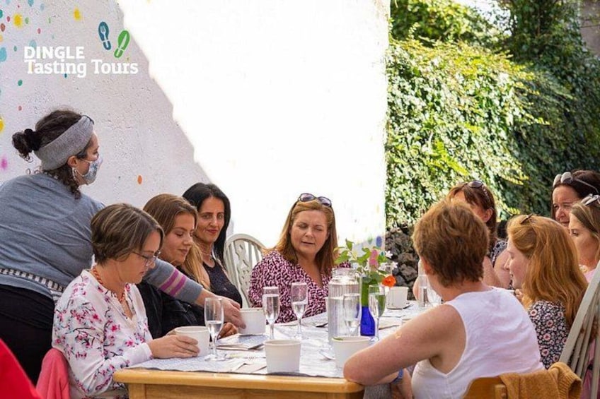 A group of people seated around a table outdoors, engaged in a tasting activity. 3