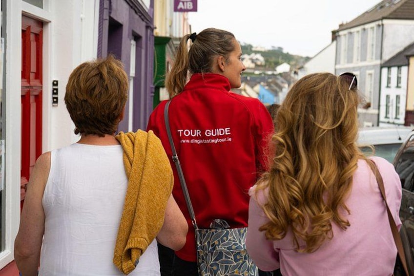 Three people walking on a street, one wearing a red jacket labeled 'TOUR GUIDE'. 5