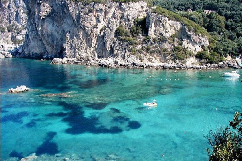 Un paysage côtier avec une eau d’un bleu limpide, des falaises rocheuses et un petit bateau. 3