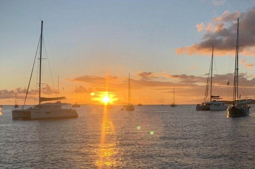 A sunset over a calm sea with several sailboats. 3