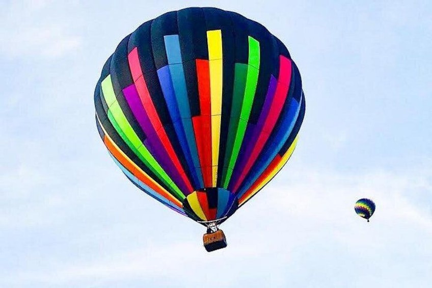 A colorful hot air balloon with stripes in various colors against a clear sky. 3