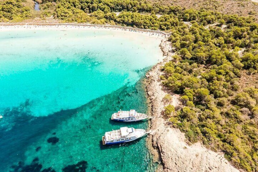 Vue aérienne d’une zone côtière aux eaux turquoise, où deux bateaux sont ancrés près du rivage, entourés d’une végétation luxuriante et d’une plage de sable. 5