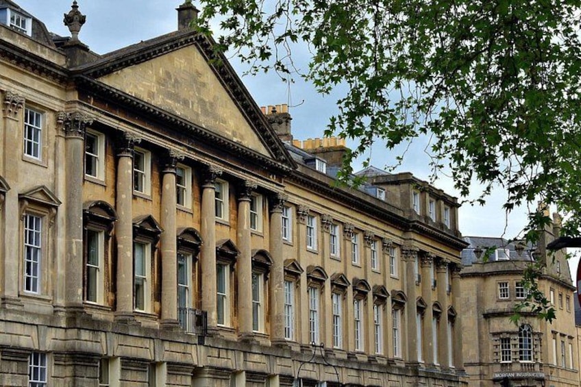 A historic building with classical architecture, featuring a symmetrical facade, large windows, and a prominent central pediment. 4
