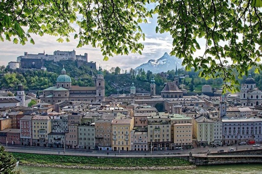 A cityscape with historic buildings, a river, and a castle in the background. 1