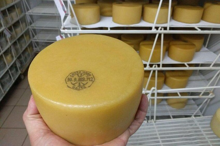 A hand holding a round cheese with a label. 2