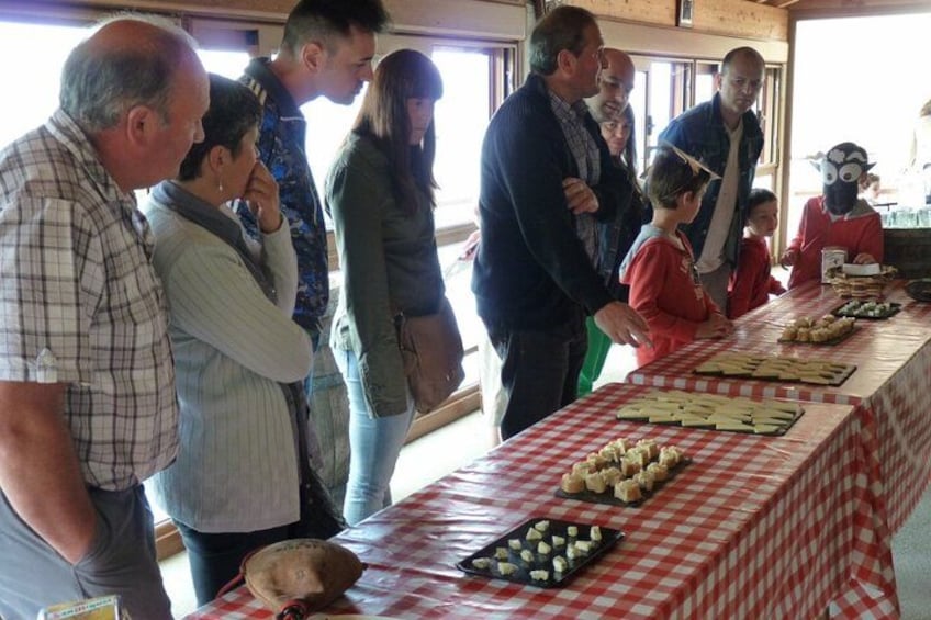A group of people at a food tasting event with a long table covered in various dishes. 5