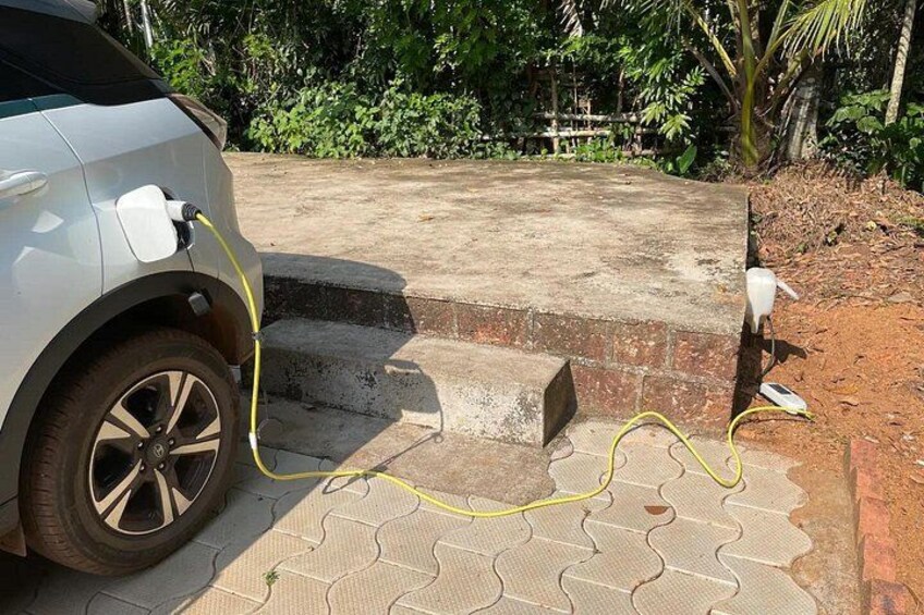 Un automóvil estacionado en una superficie pavimentada con un cable de carga conectado. 2