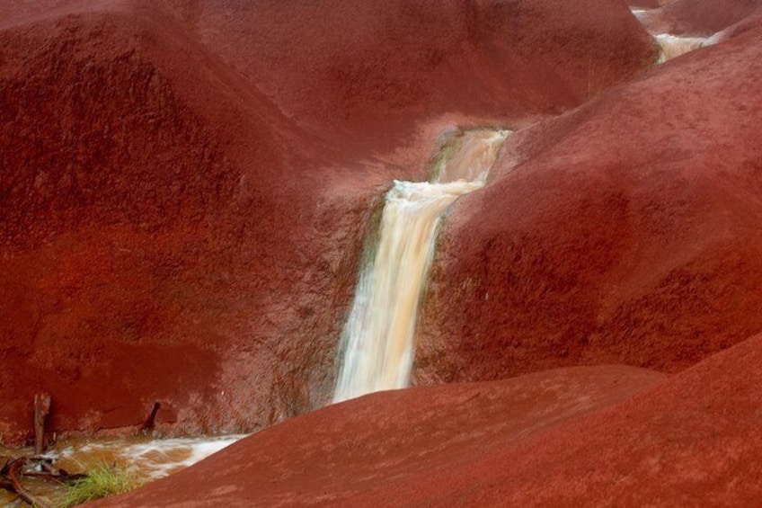 Een waterval die door een roodachtig landschap stroomt. 2