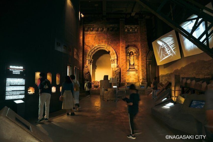 An indoor historical exhibit with stone arches, a statue, and informational displays. 3