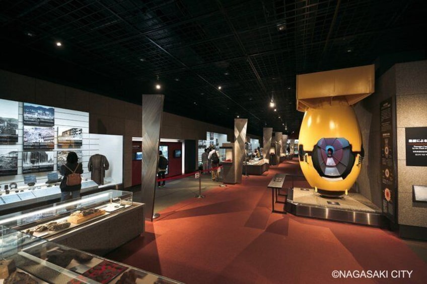 An indoor exhibition space with display cases, a large yellow sculpture, and informational panels. 2