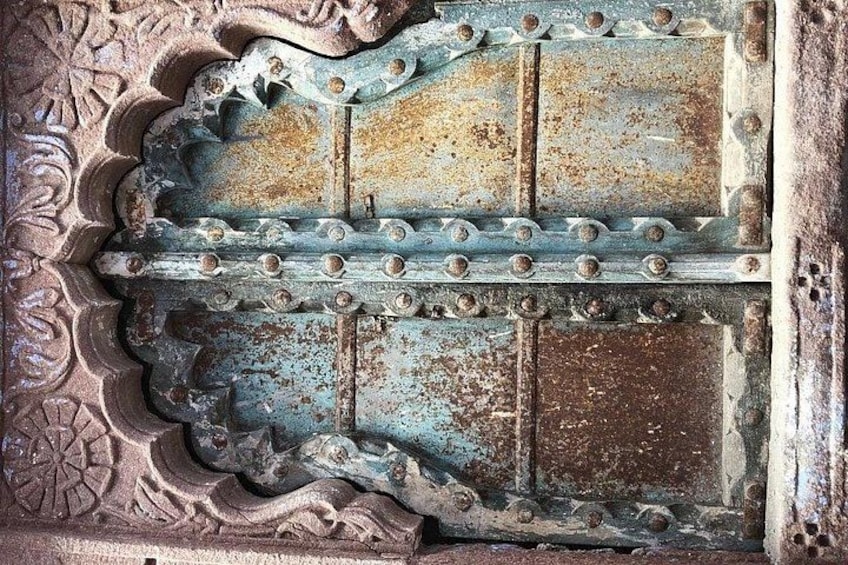 A weathered metal gate with intricate carvings and rust. 1
