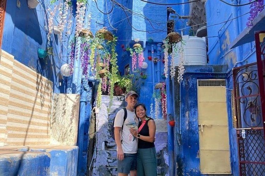 A narrow alleyway with blue walls, hanging plants, and a yellow door. 4