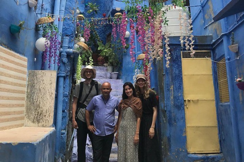 A narrow alley with blue walls, hanging flowers, and a yellow door. 2