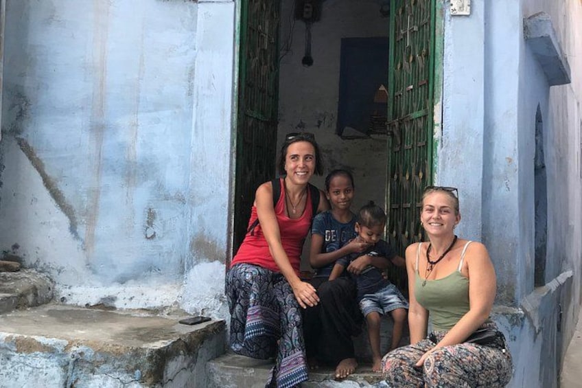A group of people sitting on steps in front of a building with a green door. 5