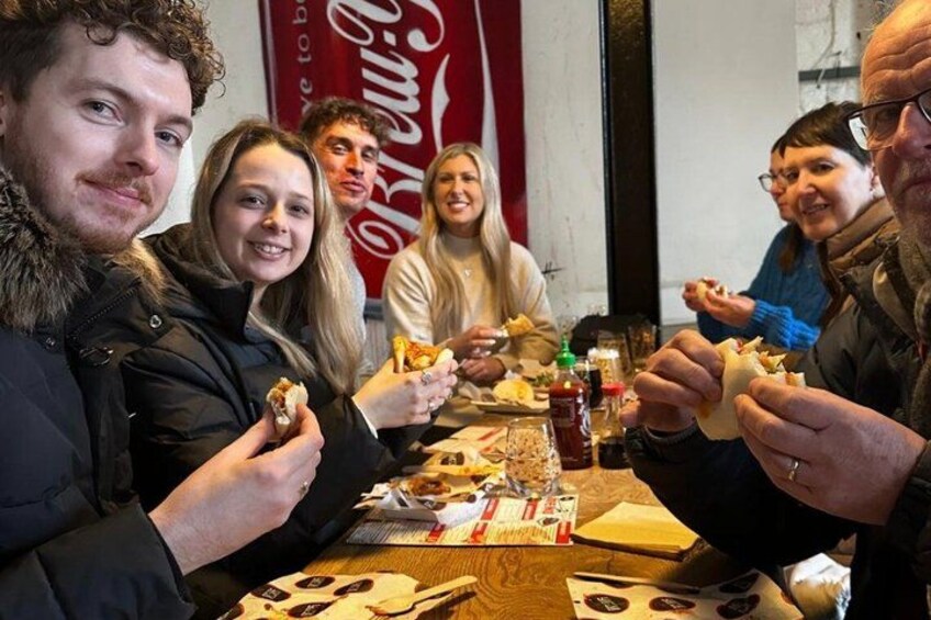 Folk sidder ved et bord med mad, et Coca-Cola skilt og en menu. 1