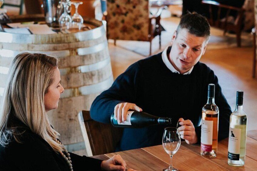 Iemand schenkt wijn in een glas aan een houten tafel in een restaurant. 1