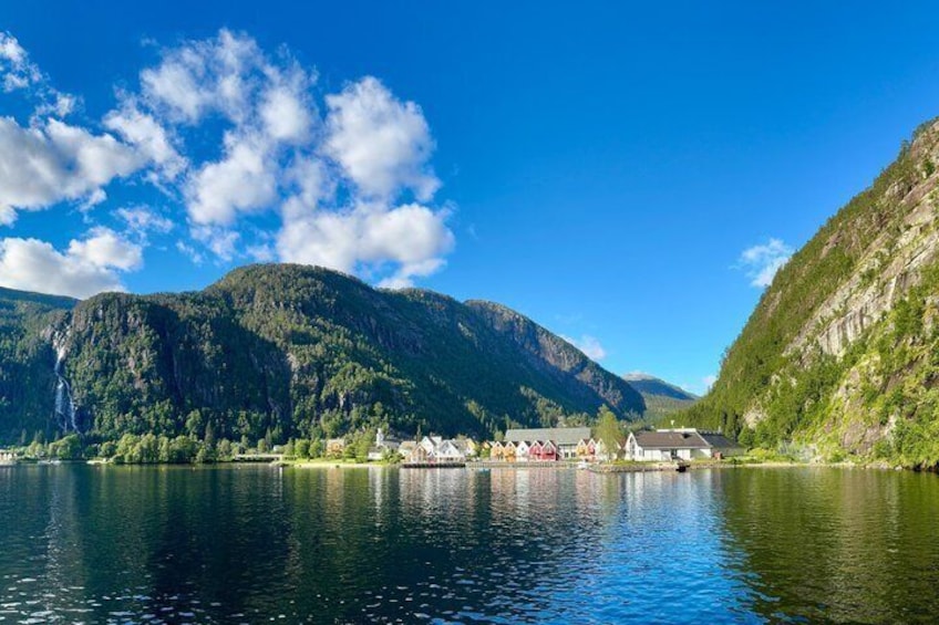 Een meer omringd door bergen, een klein dorp met huizen, en een heldere blauwe lucht. 3