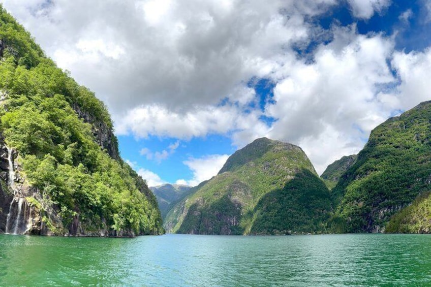 Een bergachtig landschap met een waterval en een kalm meer. 2