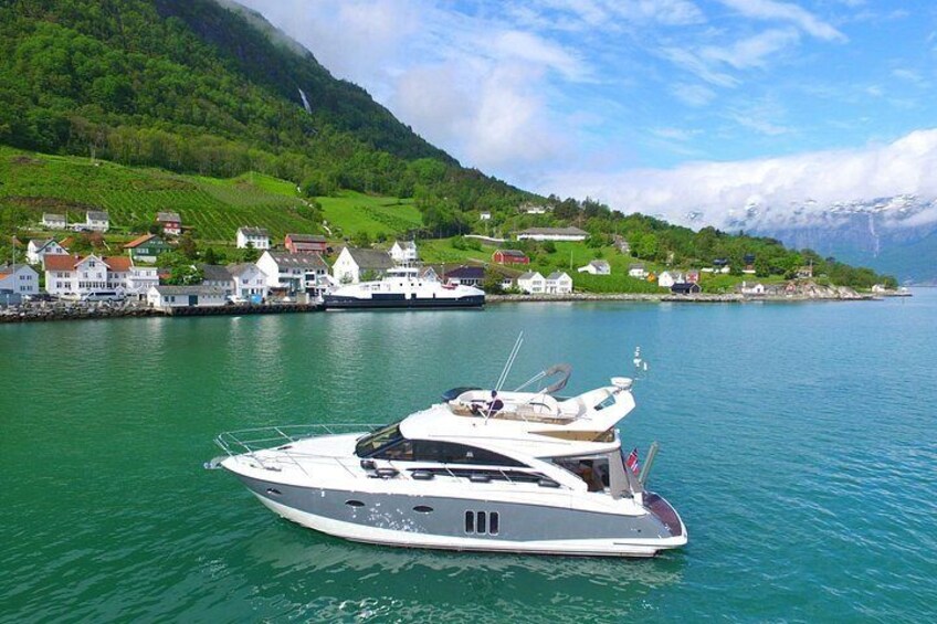 Een witte jacht afgemeerd in een haven, met huizen en begroeiing op de achtergrond. 1