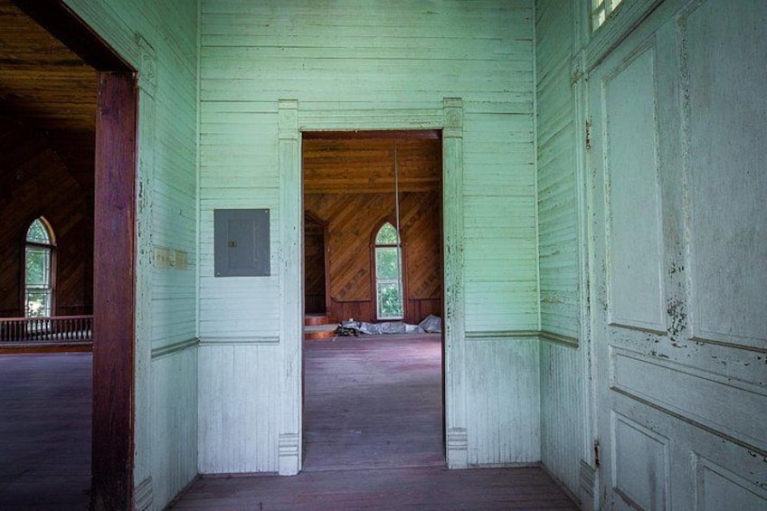 Une pièce aux murs recouverts de lambris verts, avec un plancher en bois et une grande porte en bois. 2