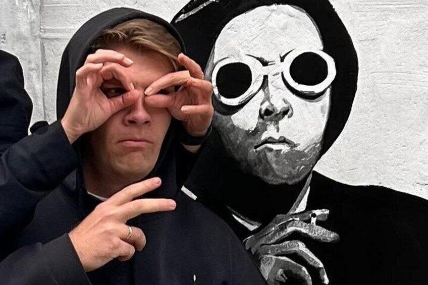 A person in a black hoodie and a black hat, pointing at something. 3