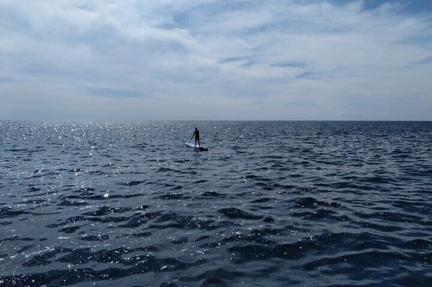 A person paddleboarding on a calm sea under a clear sky. 3