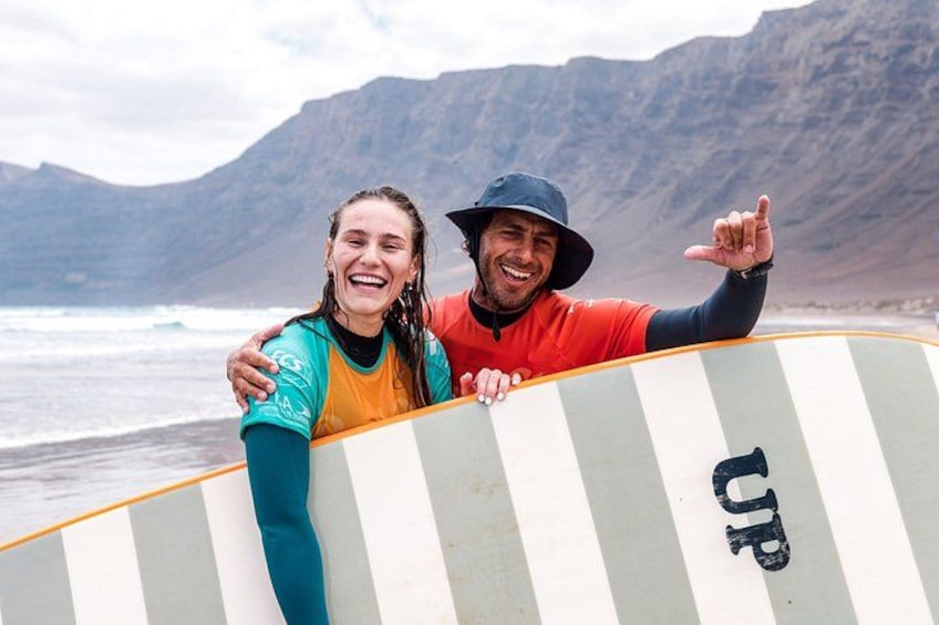 Due persone che reggono un surf con una montagna sullo sfondo. 3