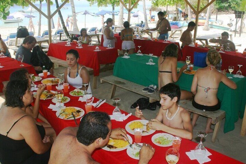 People dining at an outdoor restaurant with red tablecloths and wooden benches. 1