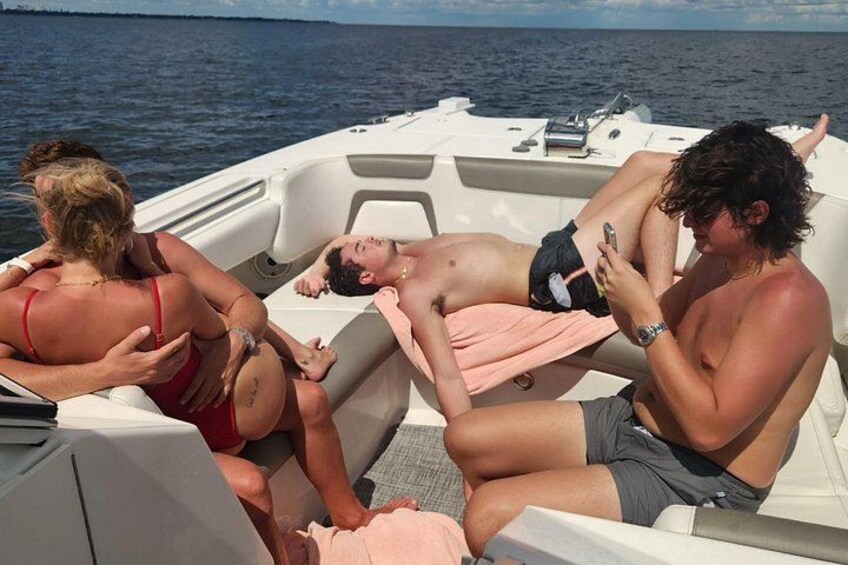 Un bateau avec trois personnes à bord : une personne est allongée et les deux autres sont assises, et le bateau se trouve sur une étendue d’eau. 4