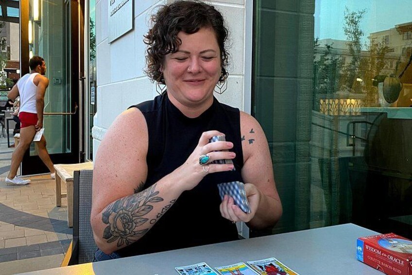 A person sitting at a table with a book and a box of cards. 4