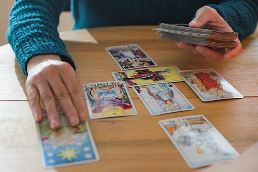 A person laying out tarot cards on a wooden table. 5