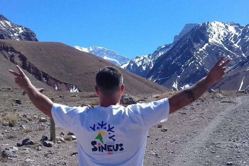 A person with arms outstretched facing a mountainous landscape. 3