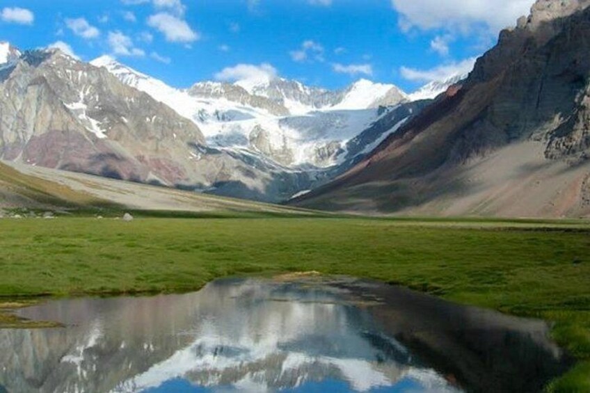 A mountainous landscape with a reflective lake, snow-capped peaks, and a clear sky. 2