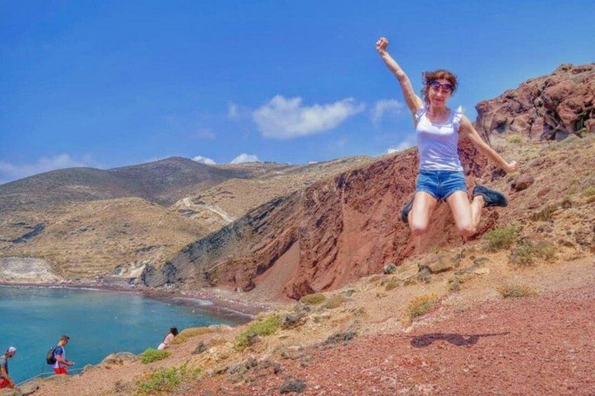 Una persona saltando por una ladera rocosa, con un paisaje costero al fondo. 1