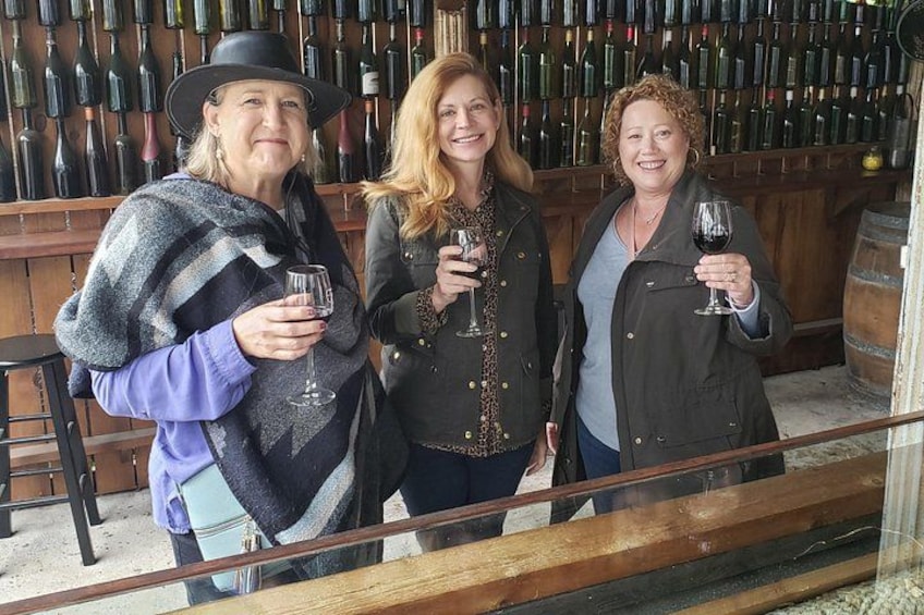 Tres personas en una bodega sosteniendo copas de vino. 4