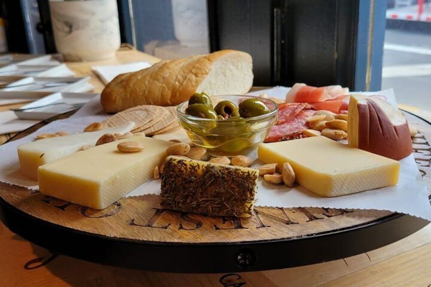 Una tabla de embutidos con quesos variados, aceitunas, frutos secos y pan. 2