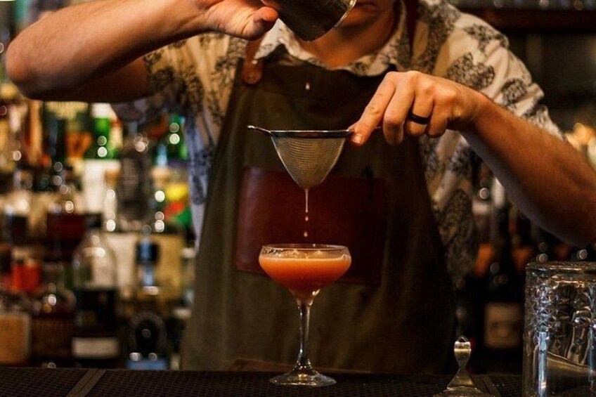 Een bartender giet een drankje in een martini glas. 3