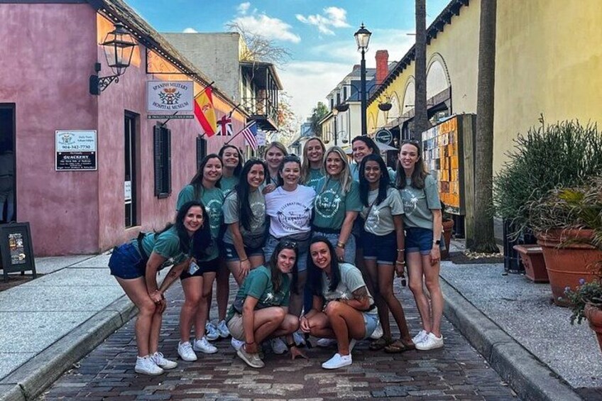 A group of people posing in a narrow street with buildings on either side. 2