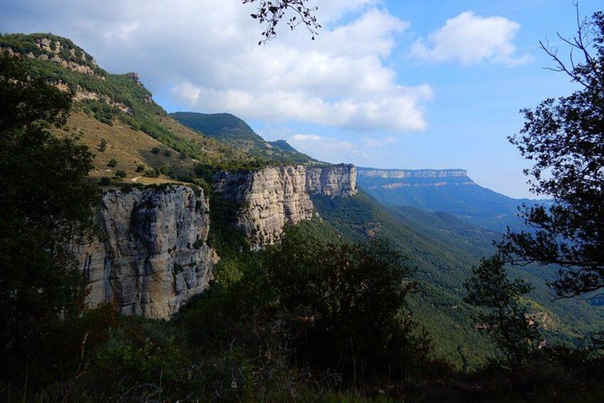 A mountainous landscape with cliffs and a distant bridge. 2