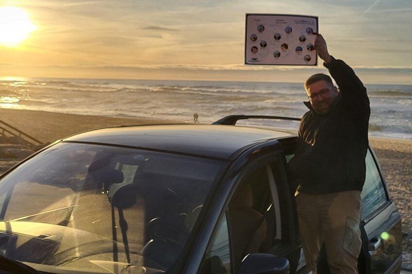 Una persona de pie junto a un coche en la playa, con el océano al fondo. 5