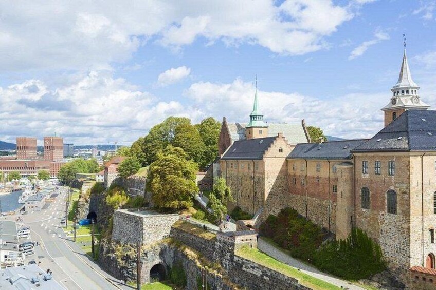 A historic stone building with a tower, a green-roofed structure, and a bridge. 4