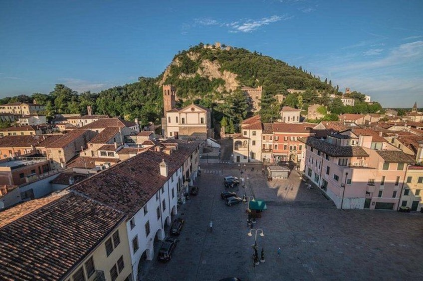 A town square with buildings, a hill with a tower, and a clear sky. 4