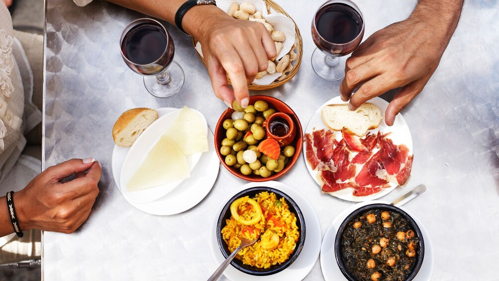 Una mesa con diversos platos, incluyendo pan, aceitunas, queso y embutidos. 5