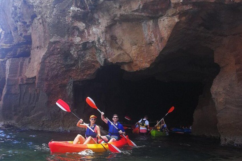 People kayaking in a cave opening surrounded by rocky cliffs. 2