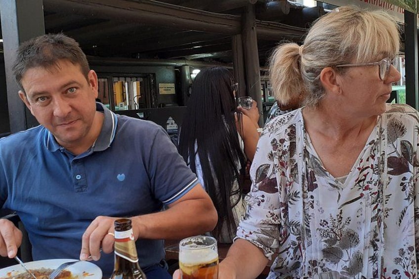 Two people sitting at a table with a bottle and a glass of beer. 2