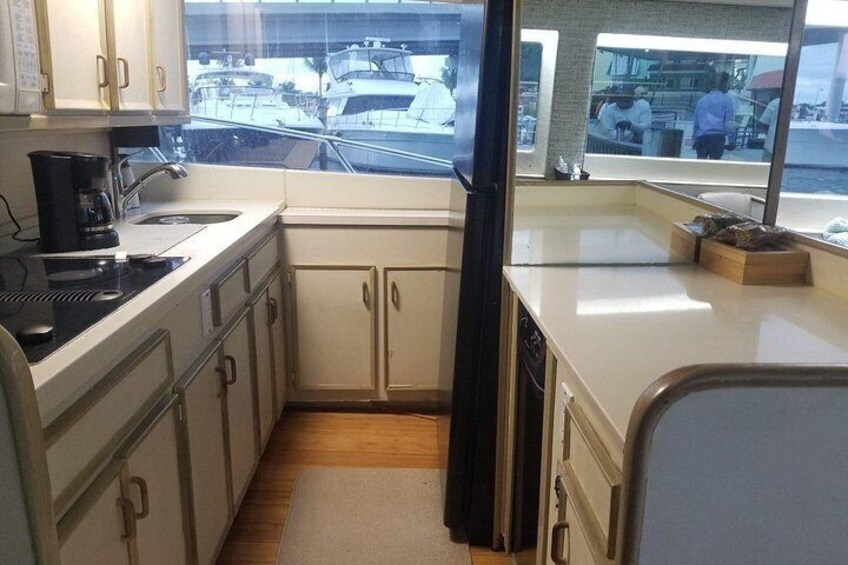 A compact kitchen with a view of boats through the window. 2