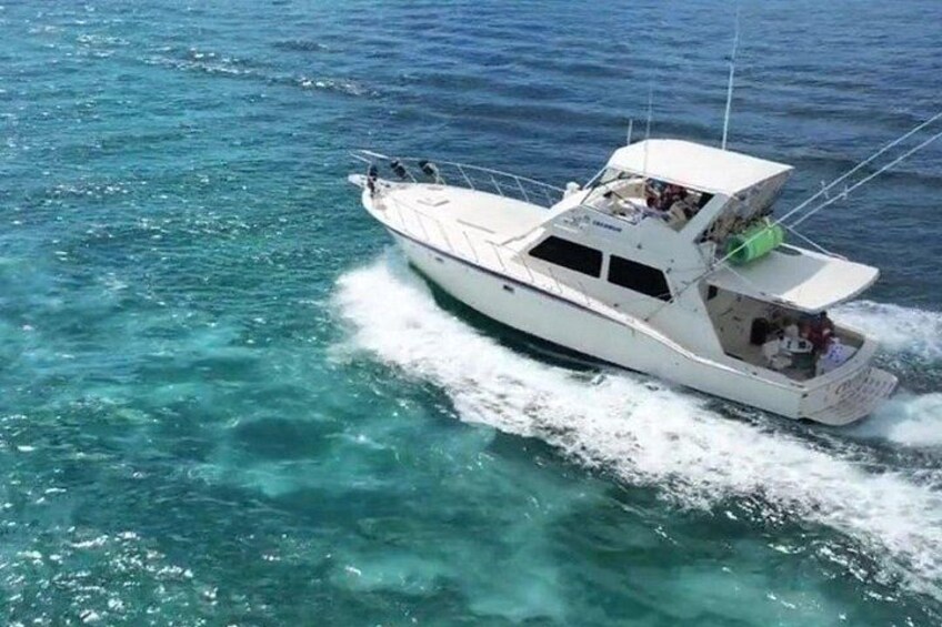 Un bote blanco con cabina y motor fueraborda verde, navegando en aguas azul cristalino. 1