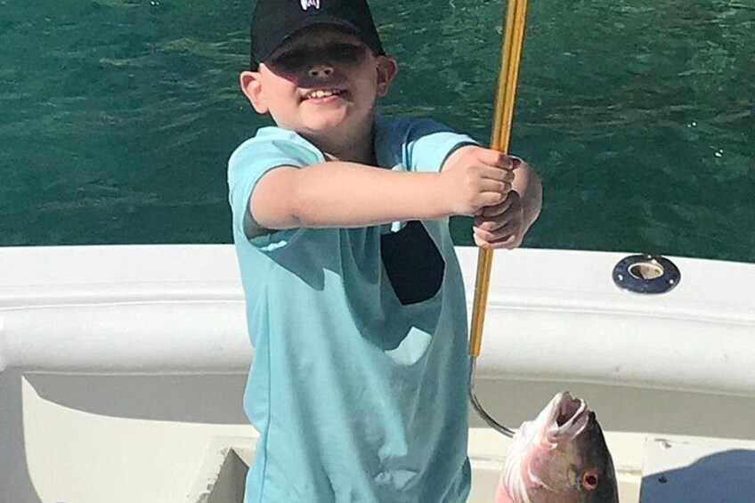 A person in a boat holding a fishing rod, with a fish in the boat. 2