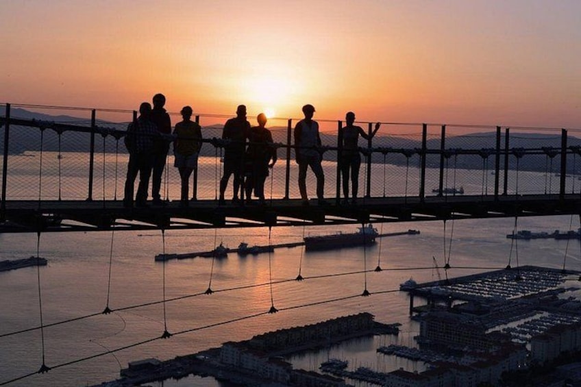 Un tramonto su un corpo d'acqua con un gruppo di persone su un ponte. 1